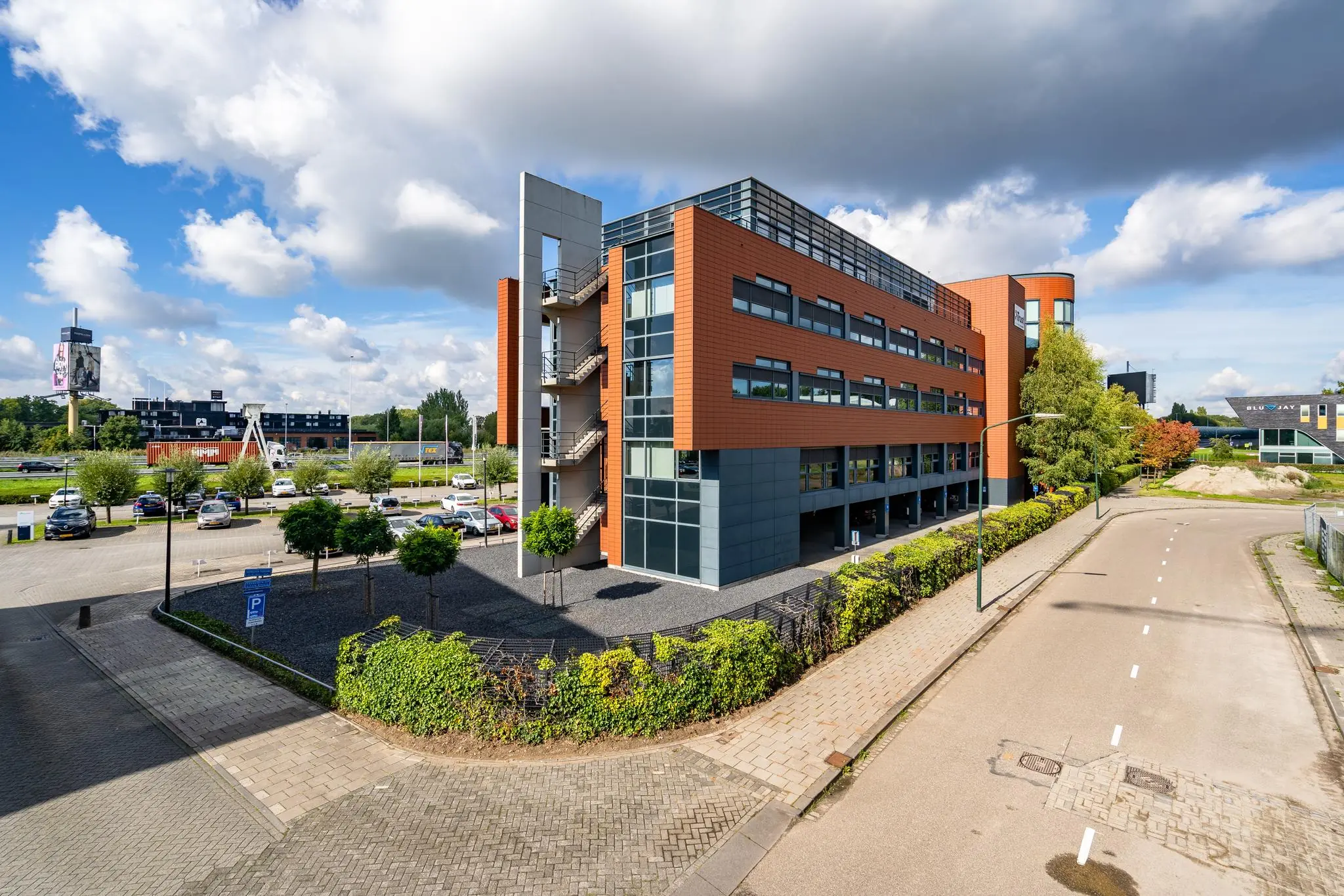 Modern kantoorgebouw aan de Laan van Barcelona met parkeerplaatsen en omliggende bedrijven.